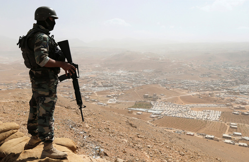 A Lebanese soldier carries his weapon as he stands on sandbags at an army post in the hills above the Lebanese town of Arsal, near the border with Syria