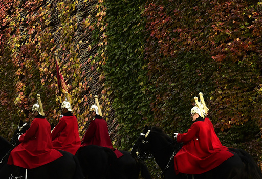 Members of the Household Cavalry ride past autumn foliage in central London, Britain