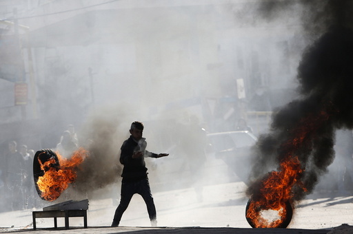 Palestinian protester runs between burning tyres during clashes with Israeli troops in the West Bank city of Hebron