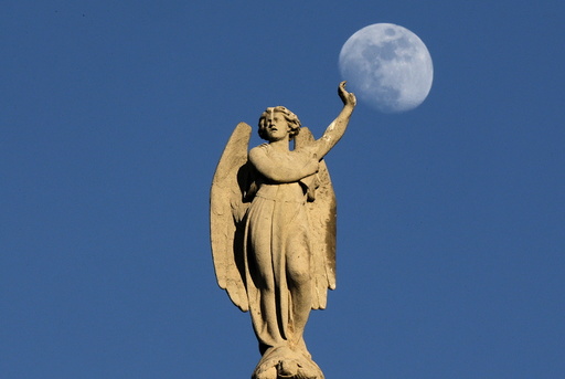 The crescent moon rises behind a statue on the Saint-Germain l'Auxerrois church in central Paris