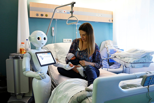 New recruit Pepper the robot holds the hand of a new born baby next to his mother at AZ Damiaan hospital in Ostend