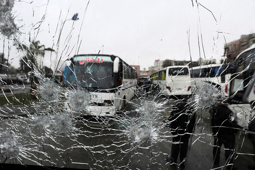 People are seen though a shattered glass window of a bus at the site of an attack by two suicide bombers in Damascus