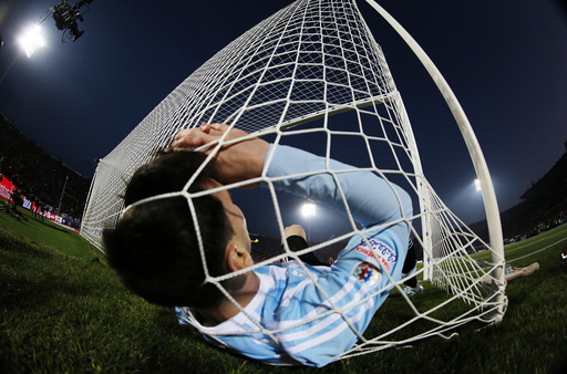 Argentina's Lionel Messi falls in the net during the Copa America 2015 final soccer match against Chile at the National Stadium in Santiago