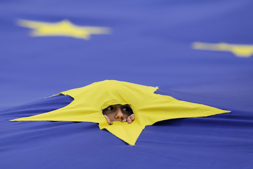 A child peers through a cut made in one of the stars that make up the European Union flag
