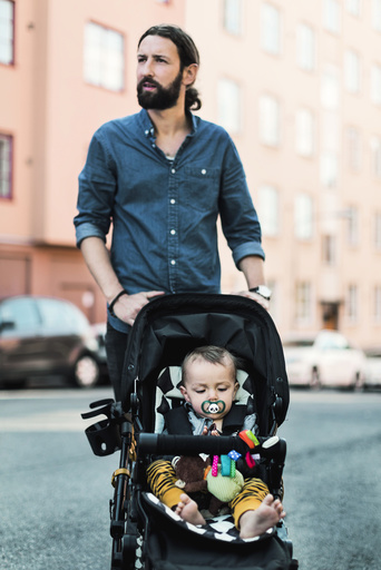 Mid adult man pushing baby in carriage on sidewalk