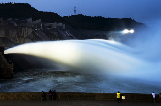 Visitors watch as water gushes from a section of the Xiaolangdi Reservoir on the Yellow River, in Luoyan