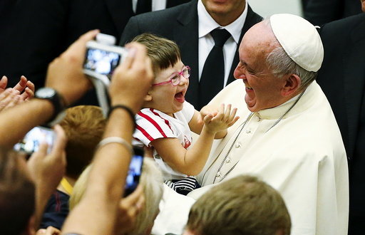 Pope Francis laughs with a baby during a special audience with parish cells for the evangelization in Paul VI hall at the Vatican