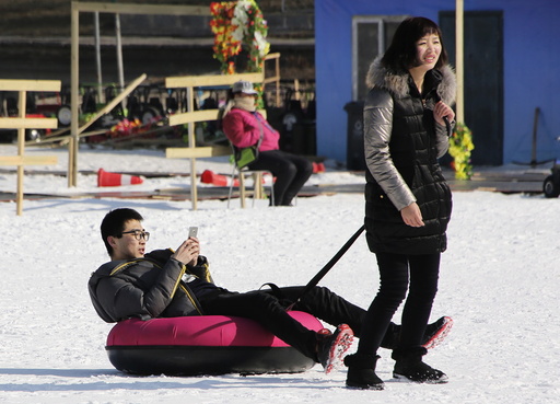 A woman toes a tube carrying a man during the Ice and snow carnival at Taoranting park in Beijing