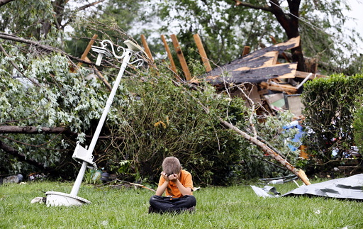 Charles Athrom, 7 sits in front of his destroyed home after a tornado swept through the area in Van, Texas