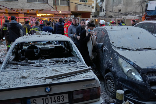 Innbyggere i Beirut blant utbrente biler på bakken nedenfor boligblokken. Foto. Hussein Malla / AP / NTB