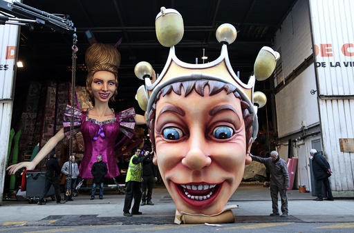 Workers hold a giant figure showing the King of Carnival during preparations for the carnival parade in Nice