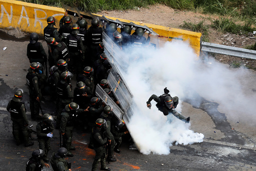A riot security forces member kicks a tear gas canister during protests at a march to state Ombudsman's office in Caracas