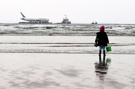 A young girl looks on at a Boeing 767 airplane in the Enniscrone estuary after being tugged from Shannon airport out to sea around the west coast of Ireland