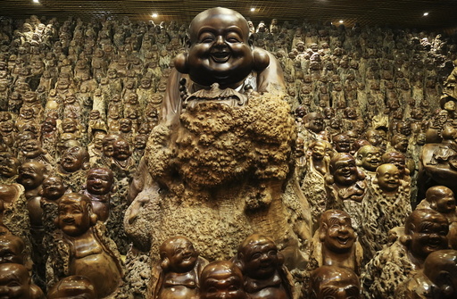 Buddha sculptures made of trunks of Chinese date trees are seen inside a room of a company selling dates, in Zhengzhou