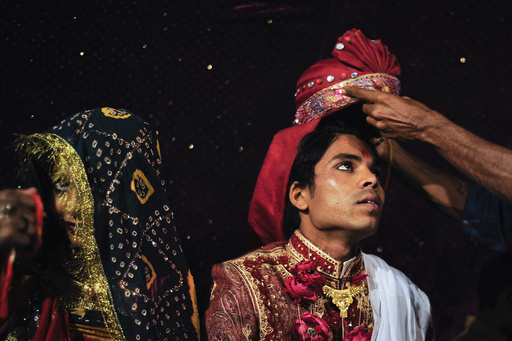 Sanjay wears a turban as he sits beside his wife Jasoda during a mass marriage ceremony in Karachi
