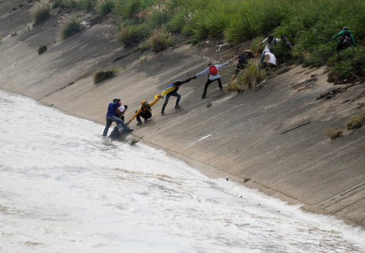 Protesters rescue a fellow protester who fell into the river during a rally in Caracas