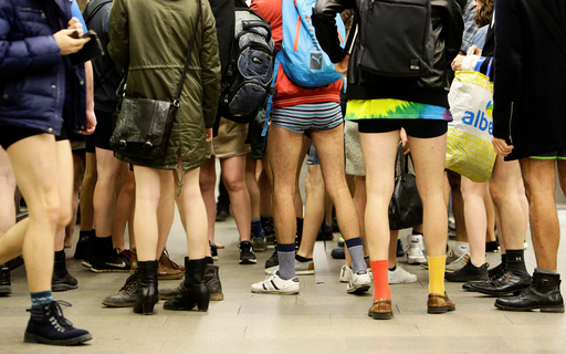 Passengers not wearing pants stand in a subway station during an annual flash mob event called the 