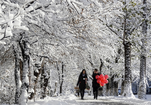 Women walk along snow-covered alley in Almaty, Kazakhstan