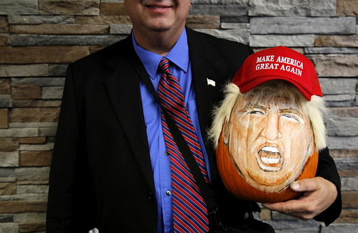 A supporter of U.S. Republican presidential candidate Donald Trump holds a pumpkin painted in the likeness of Trump as he waits to get into a campaign event in Springfield