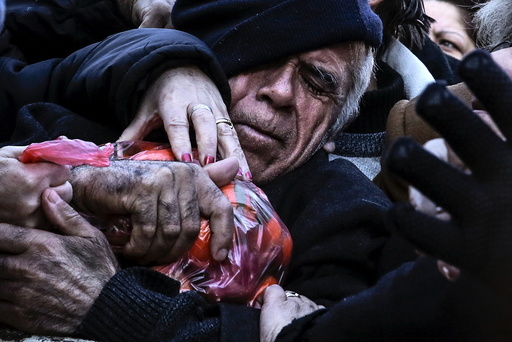 A man grasps a bag of tangerines as people receive free produce, handed out by farmers, during a protest over the government's proposal to overhaul the country's ailing pension system in Athens