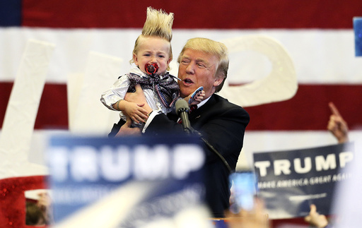 Republican U.S. presidential candidate Donald Trump holds up a crying young child from the crowd as he arrives at a Trump campaign rally in New Orleans, Louisiana