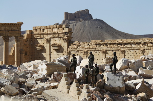 Syrian army soldiers stands on the ruins of the Temple of Bel in the historic city of Palmyra