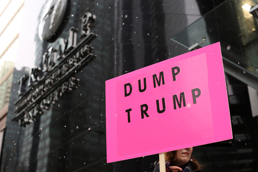 A protester holds a sign during the grand opening of the Trump International Hotel and Tower in Vancouver