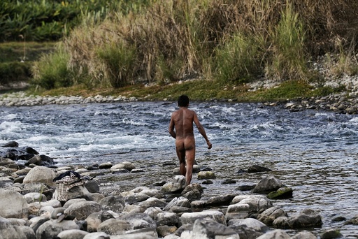 A naked Naga man looks for fish after exploding dynamite in a creek between Donhe and Lahe township in the Naga Self-Administered Zone