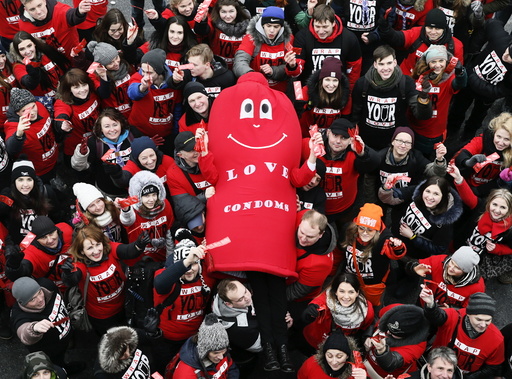 Activists hold a man dressed in a condom costume as they wave hands while marking International Condom Day at a compound of the World War Two museum in Kiev