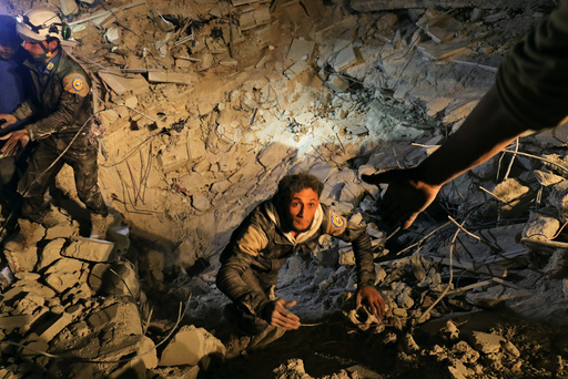 A civil defence member attempts to get out of a site hit at night by an airstrike in Saraqeb, in rebel-held Idlib province, Syria