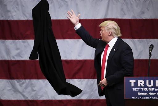 U.S. Republican presidential candidate Donald Trump tosses off his overcoat as he speaks at a campaign event in an airplane hangar in Rome, New York