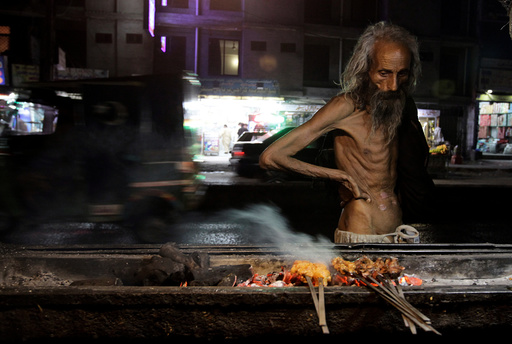 A man looks at kebabs cooking on the street side in Rawalpindi