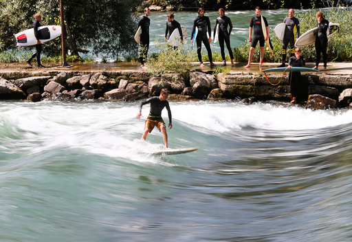 A man surfs on a wave on the Reuss river during sunny weather in the town of Bremgarten