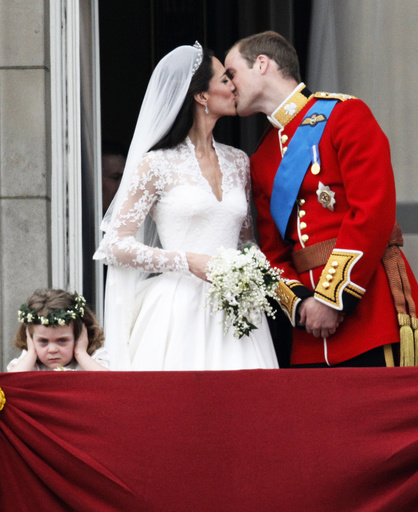 Britain's Prince William and his wife Catherine, Duchess of Cambridge, kiss as they stand next to bridesmaid Grace van Cutsem on the balcony at Buckingham Palace after their wedding in Westminster Abbey, in central London