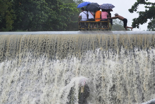 Residents cross a swelling dam, due to rising waters brought about by Typhoon Koppu, in Las Pinas city, metro Manila