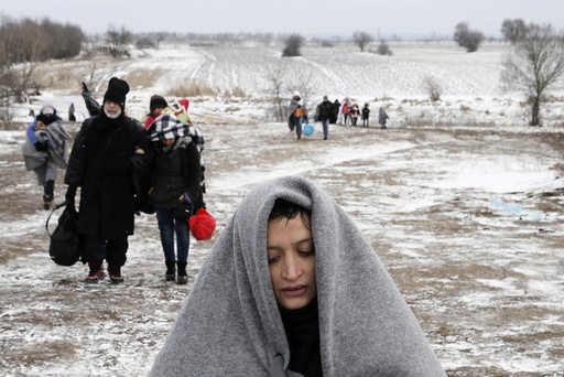Migrants walk through a frozen field after crossing the border from Macedonia, near the village of Miratovac, Serbia