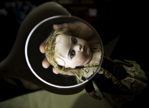 A worker examines a French bisque doll at the Vectis auction house in Stockton-on-Tees