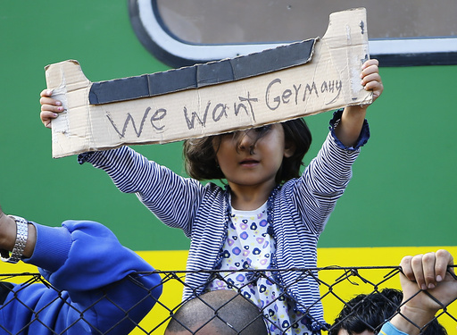 A young migrant girl holds up a sign during a protest in front of a train at Bicske railway station