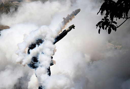 A demonstrator throws back a tear gas grenade while clashing with riot police during the so-called 