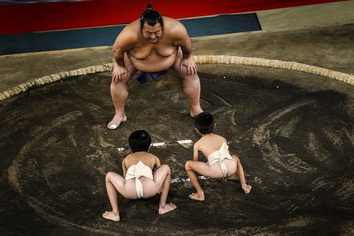 A sumo wrestler faces off two boys in a mock competition, during a presentation by professional sumo stables promoting the sport, at a department store in Tokyo