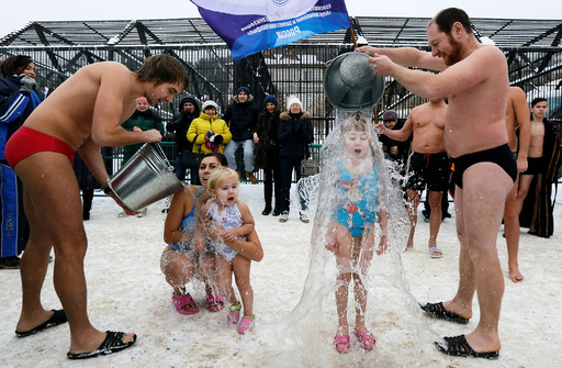Visitors watch as members of local winter swimmers club pour buckets of cold water over their daughters during celebration of Polar Bear Day at Royev Ruchey zoo in Krasnoyarsk