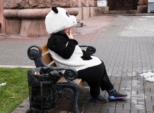 A man dressed as a panda rests and smokes in between posing for pictures with tourists in central Kiev