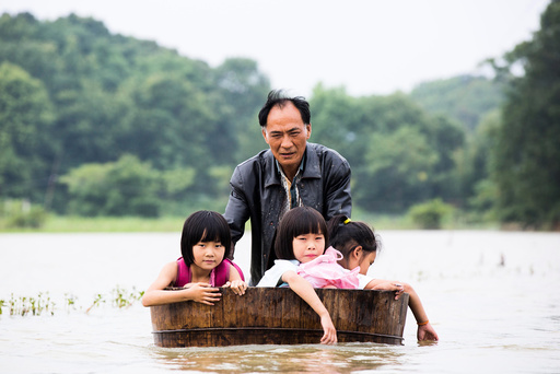 A man pushes a tub carrying children as he gets them back home after school at a flooded area in Duchang