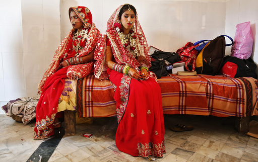 Brides sit after their make-up was done during a mass wedding ceremony at a temple in New Delhi