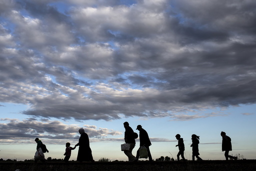 Migrants walk along rail tracks as they arrive to a collection point in the village of Roszke, Hungary