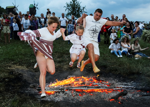 People jump over a campfire during a celebration on the traditional Ivana Kupala holiday in Kiev