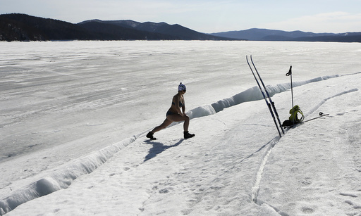 Woman wearing bikini exercises on bank of frozen Yenisei river in Taiga area south of Krasnoyarsk