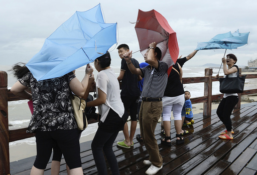 People hold onto their umbrellas as they encounter strong winds near the coast as Typhoon Utor hits Yangjiang