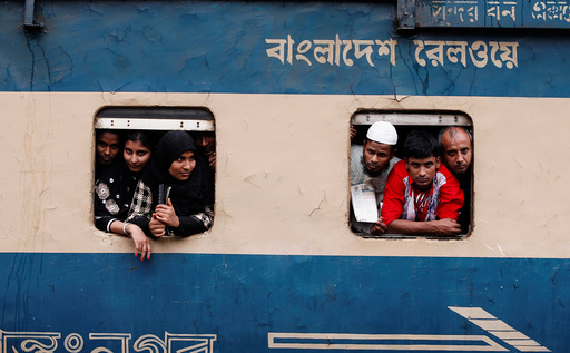 People stand in the windows of an overcrowded passenger train as they travel home to celebrate Eid al-Fitr festival, which marks the end of the Muslim holy fasting month of Ramadan, at a railway station in Dhaka