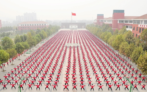 A Chinese national flag flies as students practice Taichi on a playground of a high school, during a Guinness World Record attempt of the largest martial arts display, on a hazy day in Jiaozuo